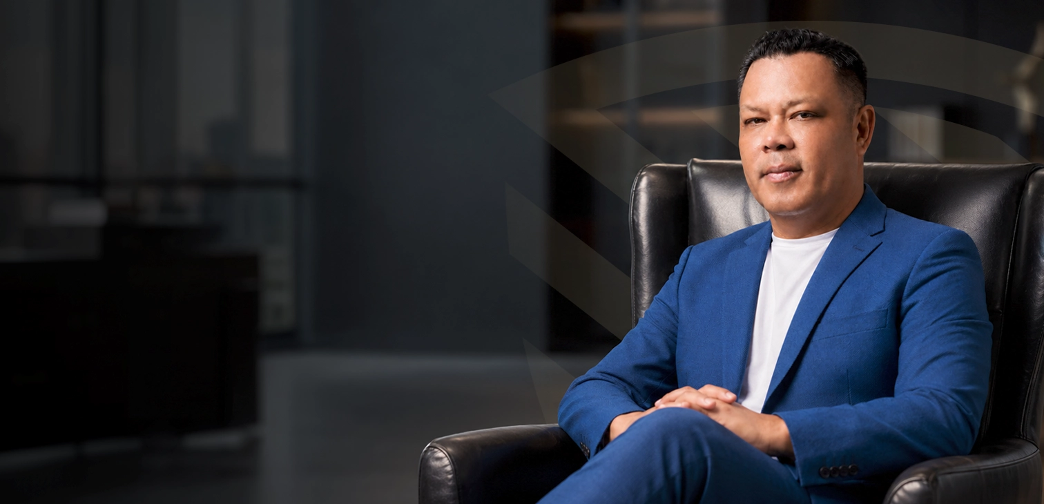 Retrato de estudio del Lic. Elías Hernández Jiménez, Presidente del Colegio Nacional de Peritos en Seguridad Laboral, sentado en un sillón ejecutivo vistiendo un saco azul.